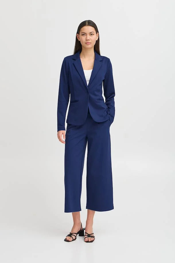 Femme portant le veston Kate de couleur bleu médiéval de la marque ICHI. Le veston a une coupe ajustée classique avec un col à revers cranté et une fermeture à un seul bouton à la taille.